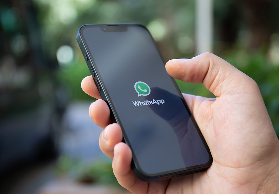 Mão a segurar um telemóvel com a aplicação WhatsApp aberta